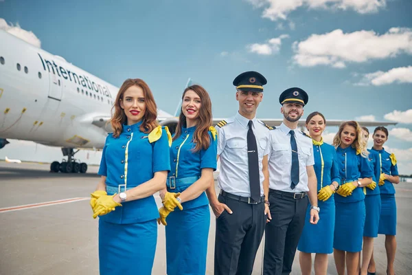 Trabajadores de aerolíneas alegres o tripulación de pie al aire libre en el campo de aviación — Foto de Stock