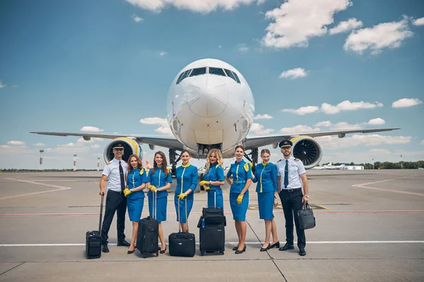 Airline workers with travel suitcases standing outdoors in airfield — Stock Photo, Image