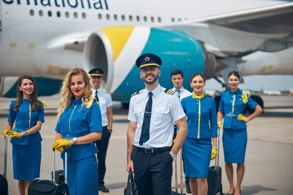 Personnel navigant joyeux avec des sacs de voyage debout à l'extérieur dans l'aérodrome — Photo