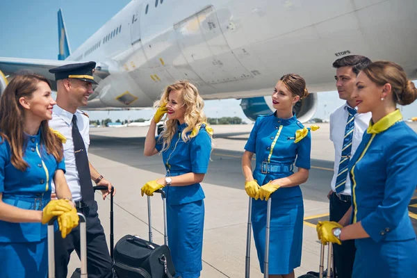 Vidám légitársaságok munkatársai beszélgetnek a repülőtéren a repülés előtt — Stock Fotó