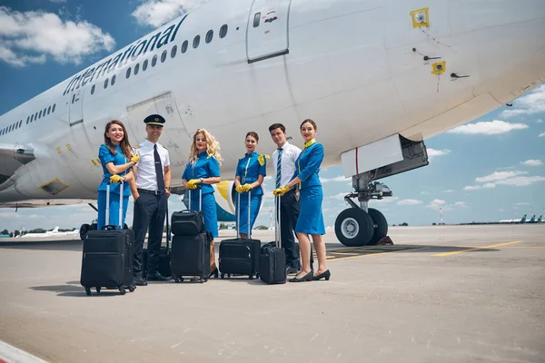 Tripulantes com sacos de viagem em pé junto ao avião — Fotografia de Stock