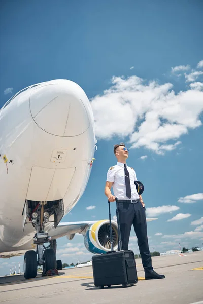 Handsome pilot with travel bag standing by the plane — Stock Photo, Image