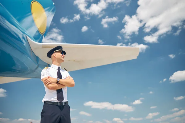 Przystojny pilot stojący przy samolocie pod błękitnym niebem — Zdjęcie stockowe