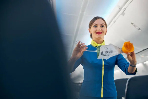 Azafata sonriente demostrando cómo usar máscaras de oxígeno para volar despega — Foto de Stock