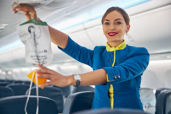 Letuška ukazuje, kam vzít kyslíkovou masku na palubu — Stock fotografie