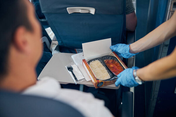 Air hostess putting meal on table gently in front of man