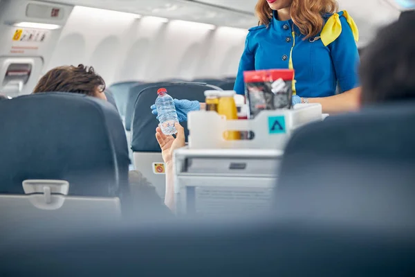 Air stewardess serving snacks from the drinks trolley — Stock Photo, Image