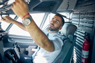Uçağın pilotu kokpit aletlerini kontrol ediyor.
