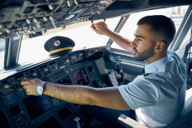 Erkek pilot, uçağın kaptanı kokpitte kalkışa hazırlanıyor.