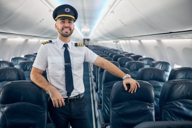 Handsome confident male posing at the camera on the board of airplane clipart