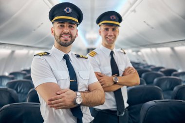 Two happy smiling men in uniform keeping arms crossed clipart