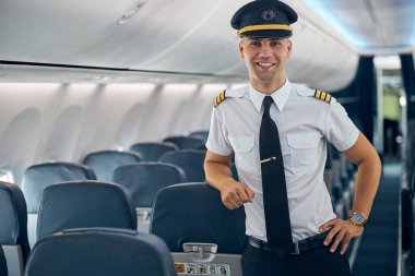 Smiling confident man in white shirt posing at the photo camera on the plane clipart