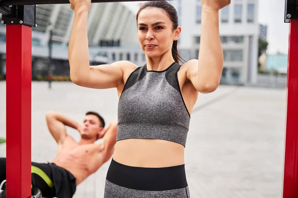 Beautiful young woman training with boyfriend outdoors — Stock Photo, Image