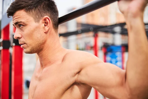 Atlético guapo hombre ejercitando en travesaño al aire libre — Foto de Stock