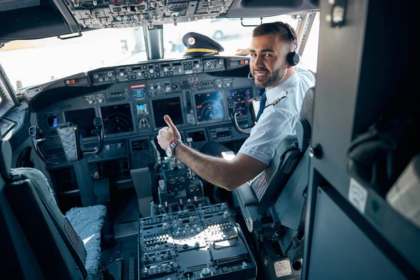 Handsome man in uniform showing like in the cabin of aircraft — Stock Photo, Image
