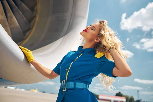 Beautiful stewardess standing by airplane at in airfield — Stock Photo, Image