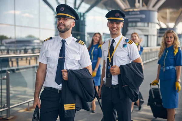 Veselí piloti a letušky stojící na ulici — Stock fotografie