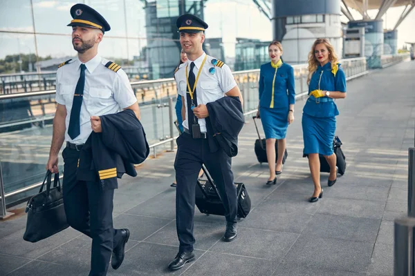 Letecká posádka s cestovními kufry chůze na ulici — Stock fotografie