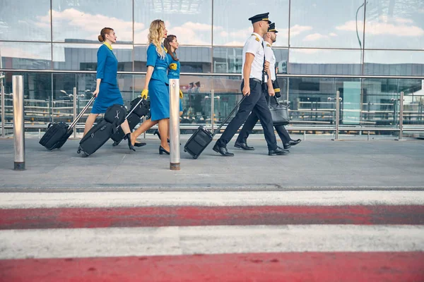Pracownicy linii lotniczych przewożący walizki podróżne na lotnisku — Zdjęcie stockowe