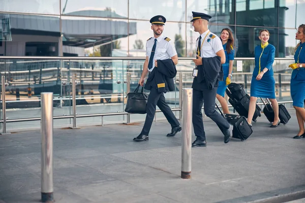Seyahat bavullu havayolu işçileri sokakta yürüyor. — Stok fotoğraf