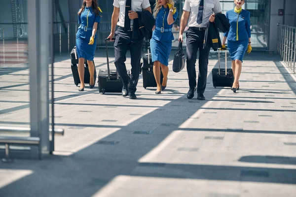 공항 터미널을 걷고 있는 여행 가방을 든 승무원들 — 스톡 사진