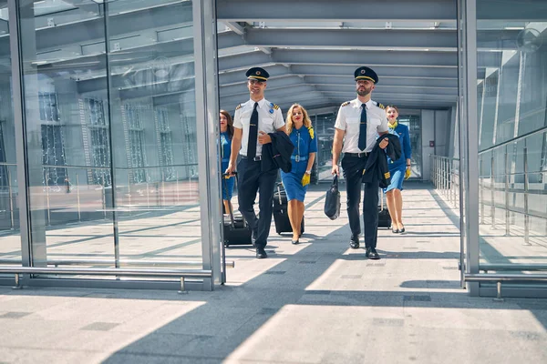 Luchtvaartpersoneel met reiskoffers die in de luchthaventerminal lopen — Stockfoto