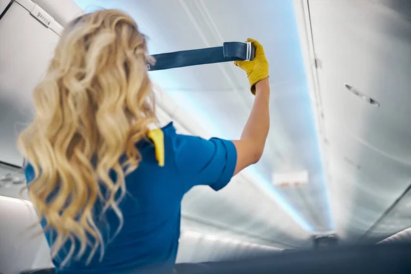 Encantadora azafata en guantes amarillos trabajando en el avión con equipos de seguridad a bordo — Foto de Stock