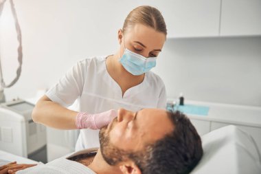 Tıraşsız genç adam iğnelenebilir cilt bakımı alıyor.