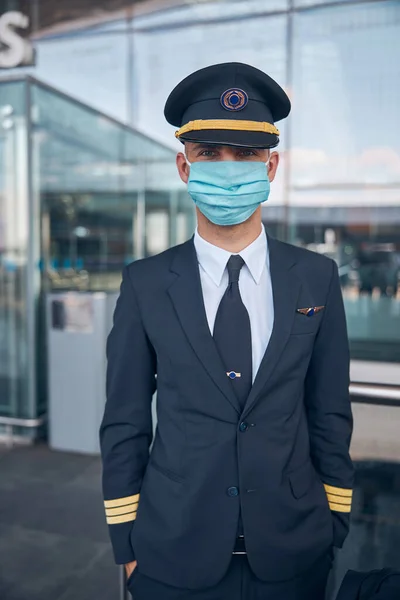 Guapo piloto masculino en máscara médica de pie en la calle — Foto de Stock