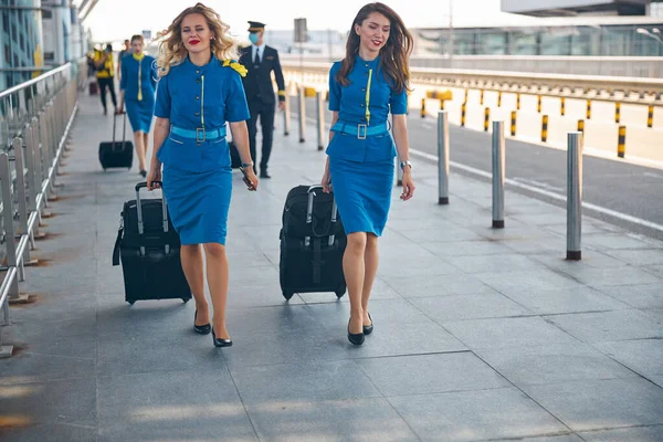 通りを歩く旅行スーツケース付きの美しいスチュワーデス — ストック写真