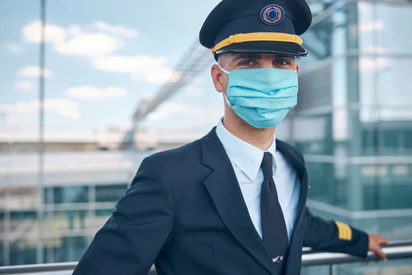 공항 터미널에서 있는 의료용 마스크를 쓴 남자 조종사 — 스톡 사진