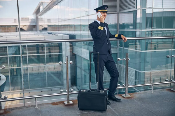 Snygg manlig pilot talar på mobiltelefon på flygplatsen — Stockfoto