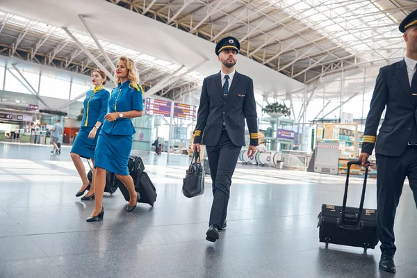 Працівники авіакомпанії, що перевозять туристичні сумки в терміналі аеропорту — стокове фото