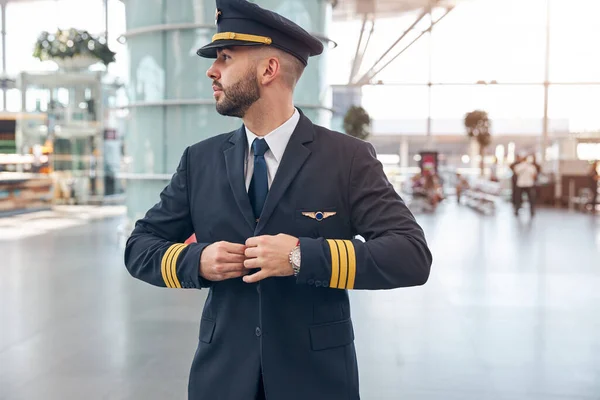Handsome male pilot buttoning up his jacket — Stock Photo, Image