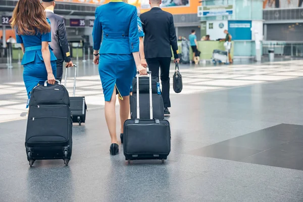 Repülőtéri terminálon utazó bőröndöket szállító légiutas-kísérő személyzet — Stock Fotó