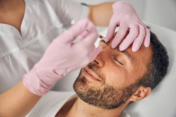 Bonito jovem recebendo injeções de cosméticos na clínica de bem-estar — Fotografia de Stock