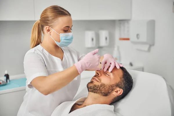 Kvinnlig läkare kosmetolog att göra injektion i mannen panna — Stockfoto
