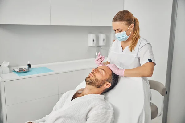 Cosmetologista feminino encantador fazendo injeção na testa do homem — Fotografia de Stock