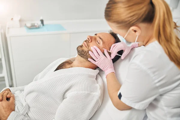 Female doctor cosmetologist making injection into male face — Stock Photo, Image