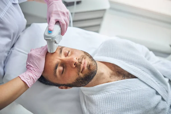 Esteticista feminina tratando a pele masculina com dispositivo laser — Fotografia de Stock