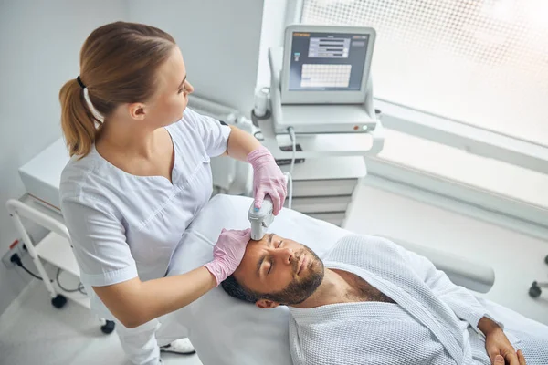 Stilig ung man som får laseransiktsbehandling på kosmetologisk klinik — Stockfoto