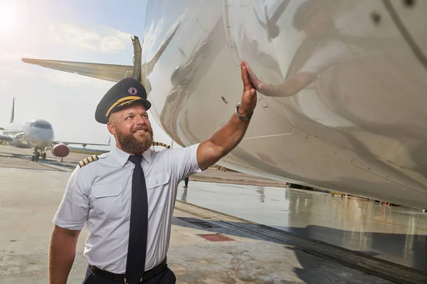 Contented pilot checking the condition of fuselage before the flight — Stock Photo, Image