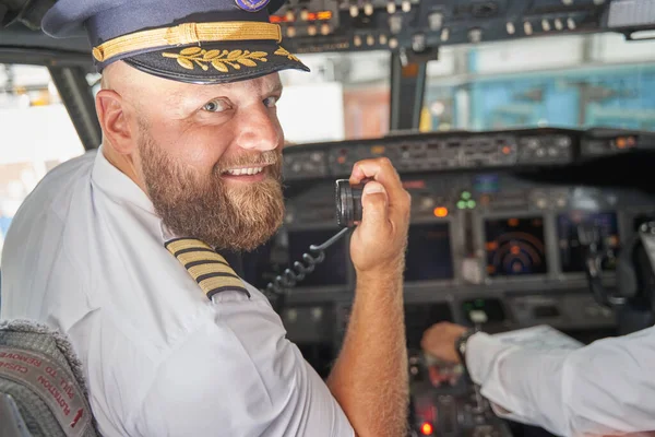 Piloto amigável sorrindo e anunciando o início do voo — Fotografia de Stock