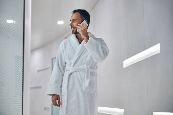 Веселый молодой человек разговаривает по мобильному телефону в оздоровительном центре — стоковое фото