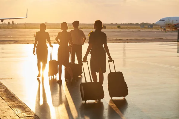 Luz del sol de la noche brillante en el aeropuerto y miembros de la tripulación caminando — Foto de Stock