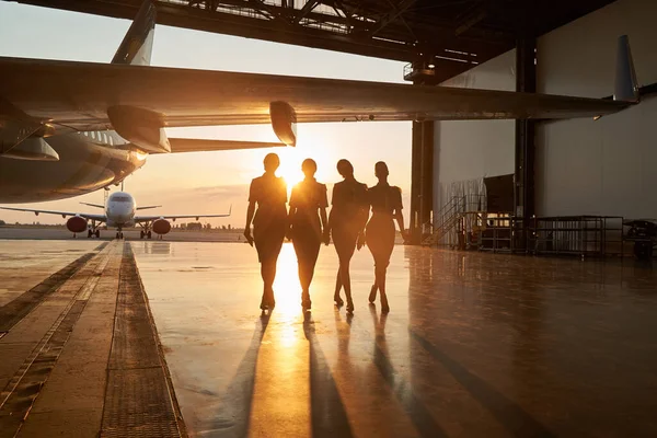 Unidentifiable stewardesses in the sunset light in hangar — Stock Photo, Image