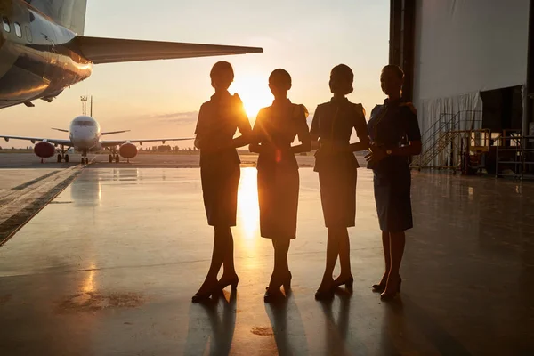 Señoras atractivas posando juntas en el hangar del aeropuerto — Foto de Stock