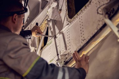 Bakım teknisyeni elinde havacılık teçhizatıyla uçakta çalışıyor.