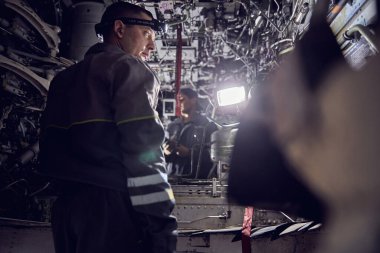 Yetişkin tamirci büyük bir uçağın jet motorunu inceliyor.