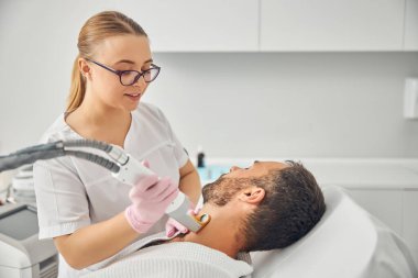 Lazer tüy çıkarma prosedürü olan yakışıklı bir genç.